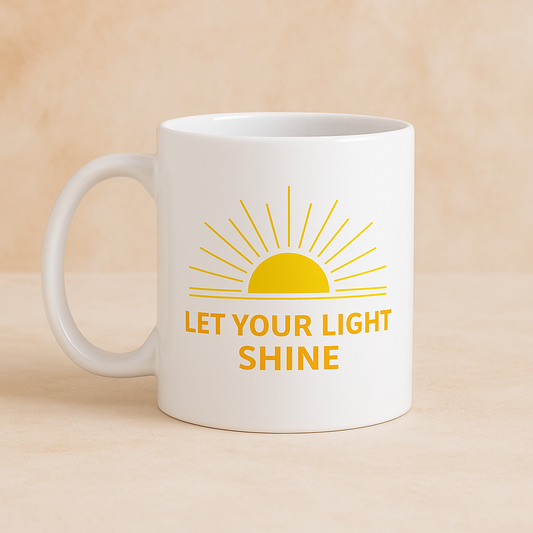 White mug with yellow sun graphic and 'Let Your Light Shine' text in orange