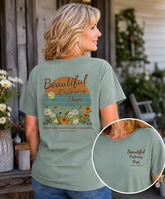 Beautiful Ordinary Days Comfort Colors Bay T-Shirt worn by a mature woman in a rustic outdoor setting, featuring a vintage floral sunset design on the back and a coordinating left chest graphic.