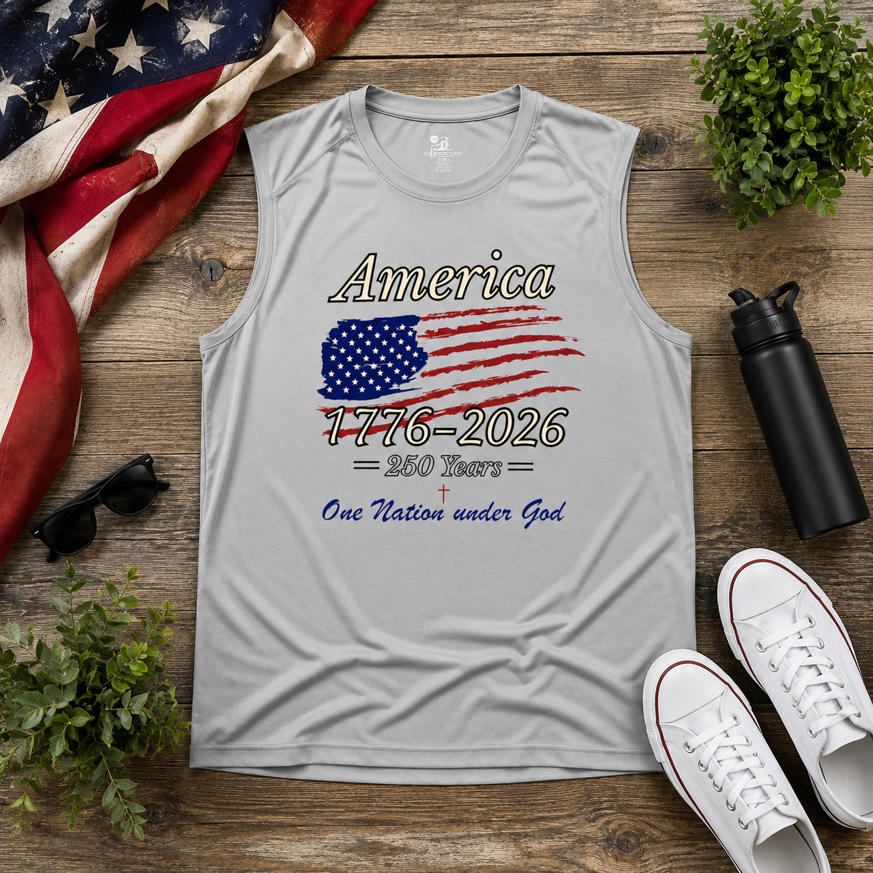 Gray patriotic muscle tank with American flag graphic and “America 1776–2026 250 Years One Nation Under God” design displayed on rustic wood background with patriotic accessories.