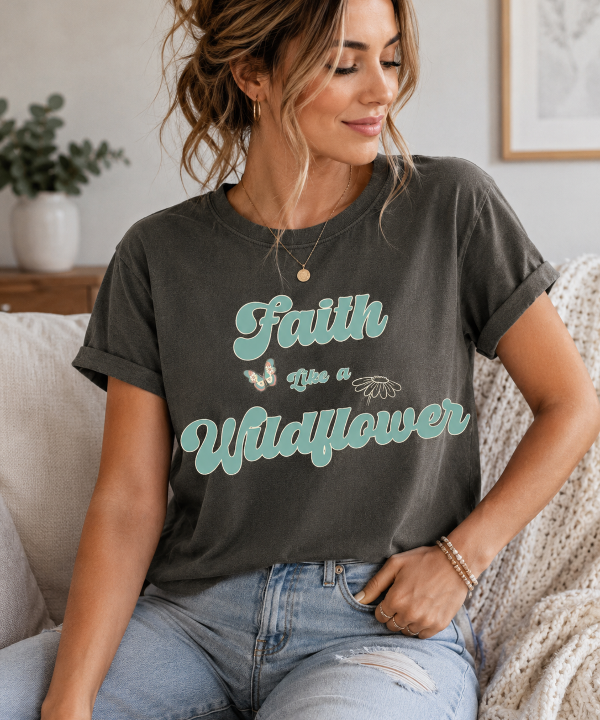 Woman wearing a vintage-inspired Comfort Colors denim blue t-shirt featuring the Faith Like a Wildflower graphic in soft teal and cream. The retro floral-inspired design includes a butterfly and wildflower illustration, creating a cozy nostalgic aesthetic perfect for everyday casual wear.