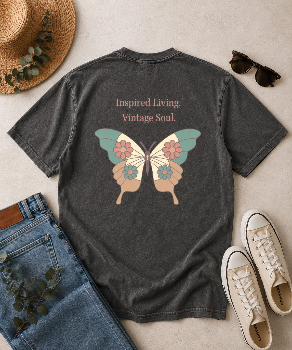 Comfort Colors Pepper t-shirt flat lay featuring the Inspired Living Vintage Soul butterfly graphic on the back. Vintage-inspired floral butterfly design with soft pastel colors, displayed with denim jeans, sneakers, and rustic accessories.