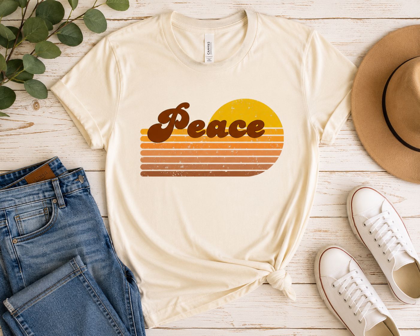Peace Retro Revival Graphic Tee displayed as a flat lay featuring distressed retro lettering and classic 70s sunset stripes on natural bella & canvas tee