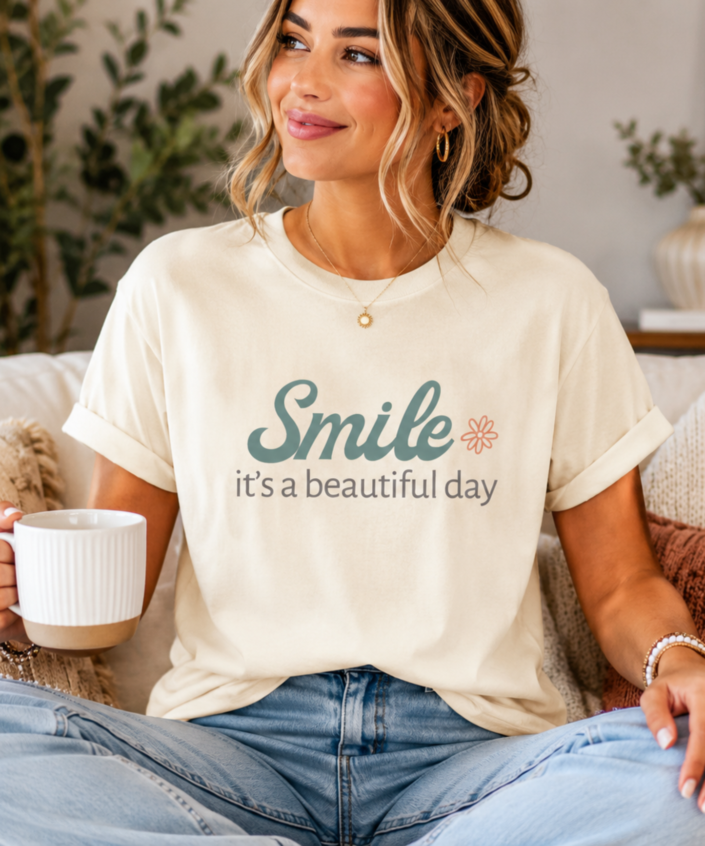 Woman wearing a cream Smile It's a Beautiful Day t-shirt paired with jeans in a bright modern home setting.